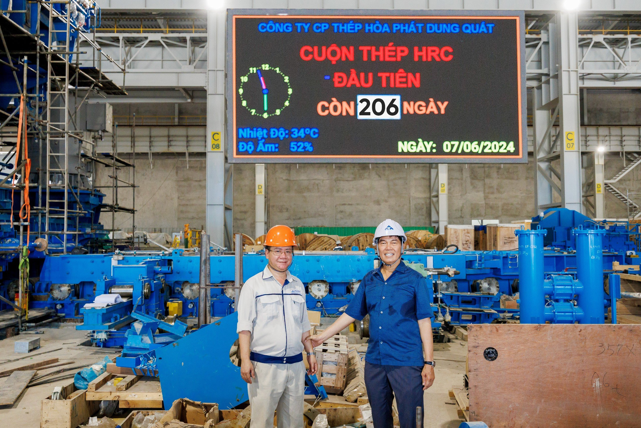   Chủ tịch Trần Đình Long và anh Bùi Văn Tiệp, Giám đốc Nhà máy cán thép QSP tại bảng đếm ngược cuộn HRC đầu tiên của Dự án Dung Quất 2 còn 206 ngày
